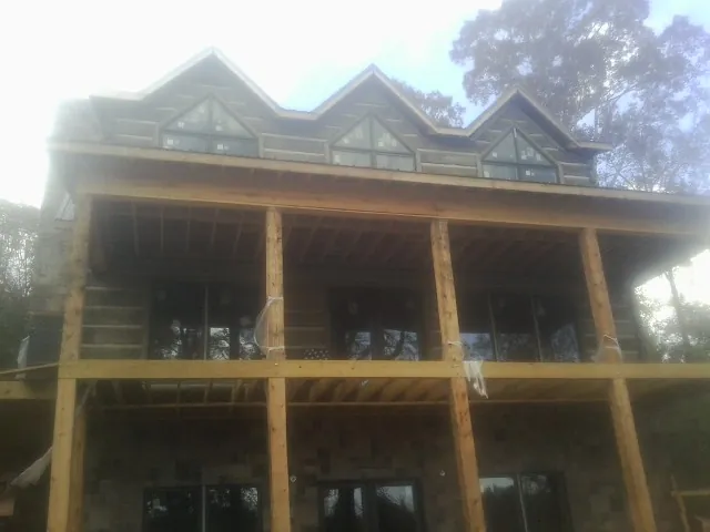Dormers and porch framing on a large log home under construction — Roof Coating work by our crew in Nottingham